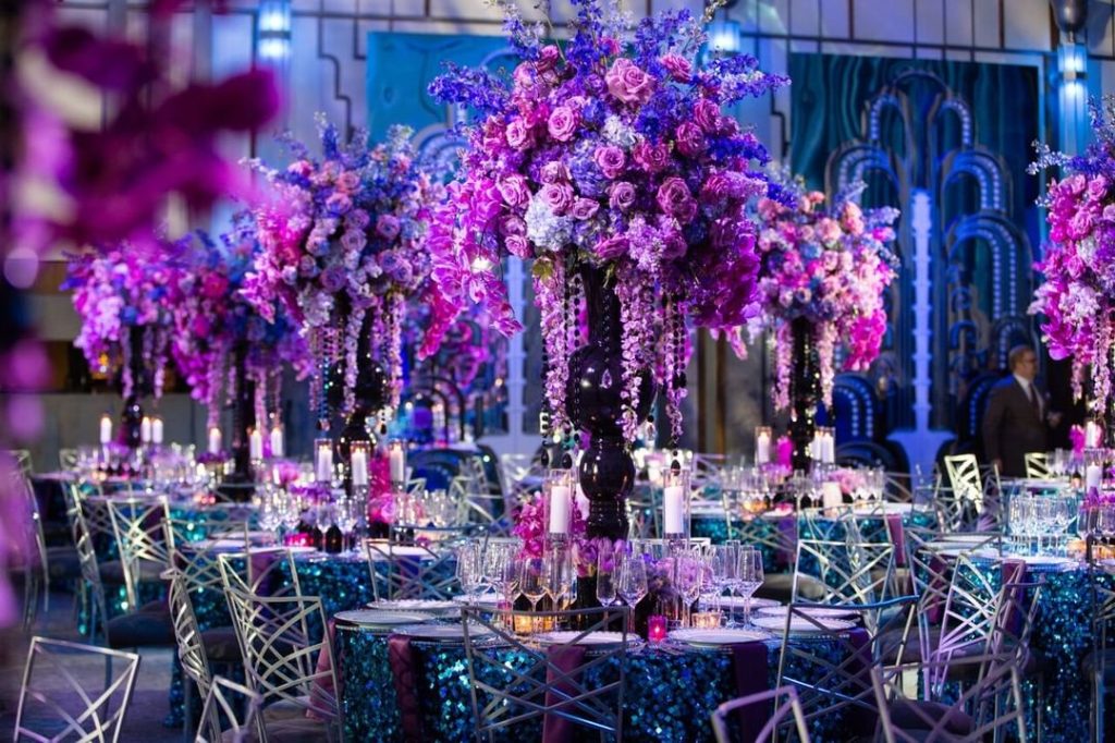 Silver fanfare event chair rentals for a luxury wedding in New York with rich, purple floral centerpieces.