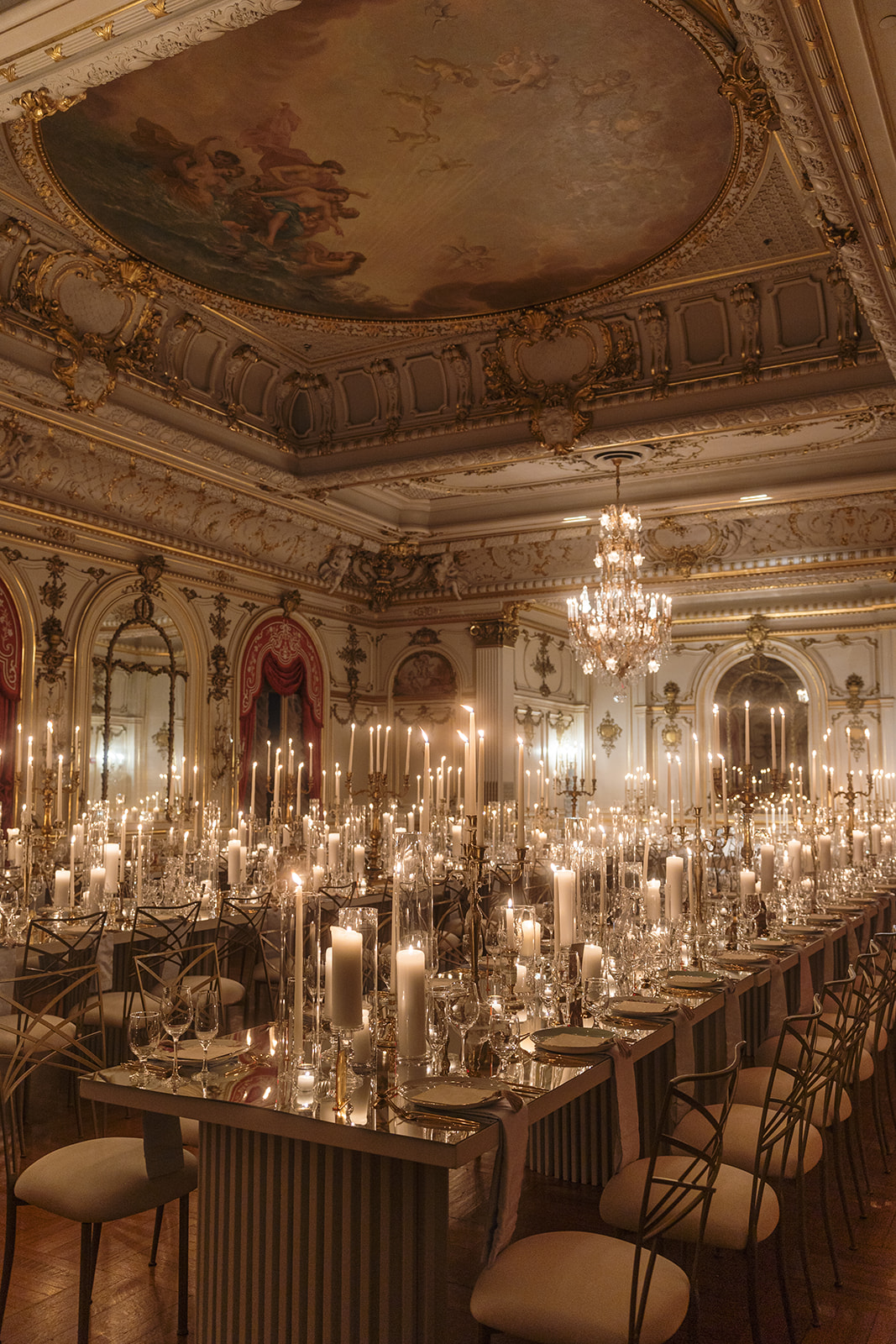 Grand ballroom setting featuring historic ceiling frescoes, massive mirrors, and structured wedding seating